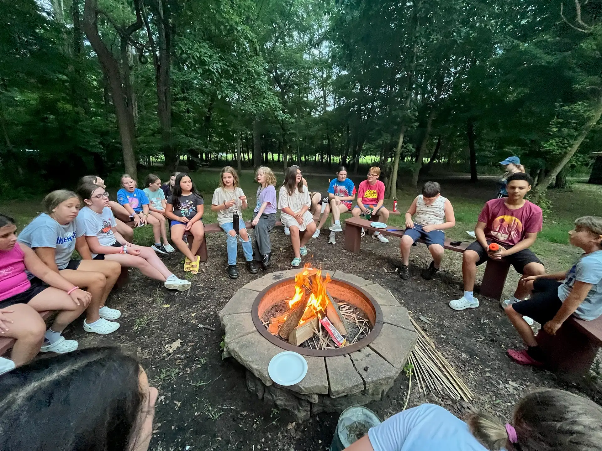 Campers gathered around a bonfire in the woods