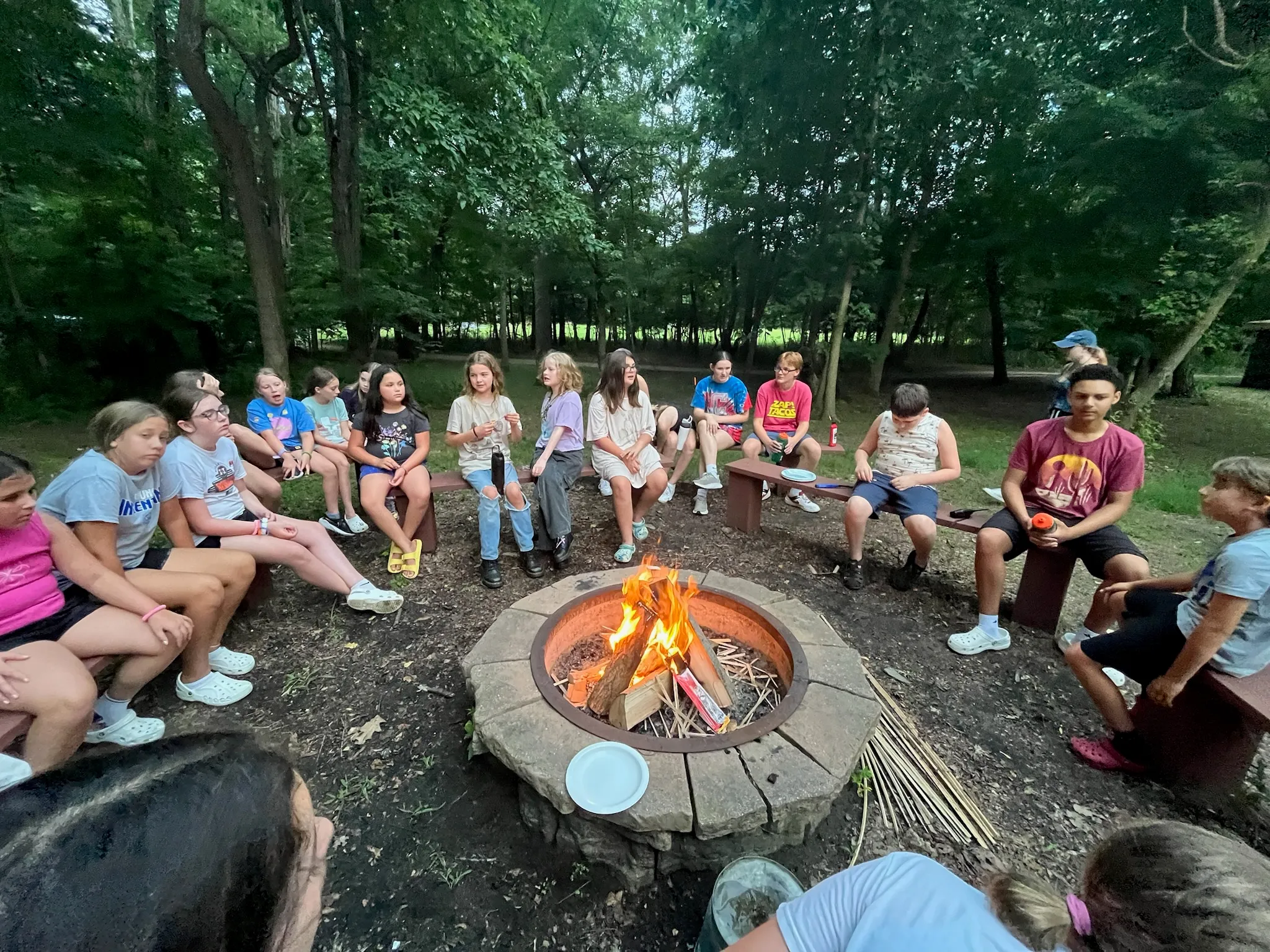 Campers gathered around a campfire in the woods