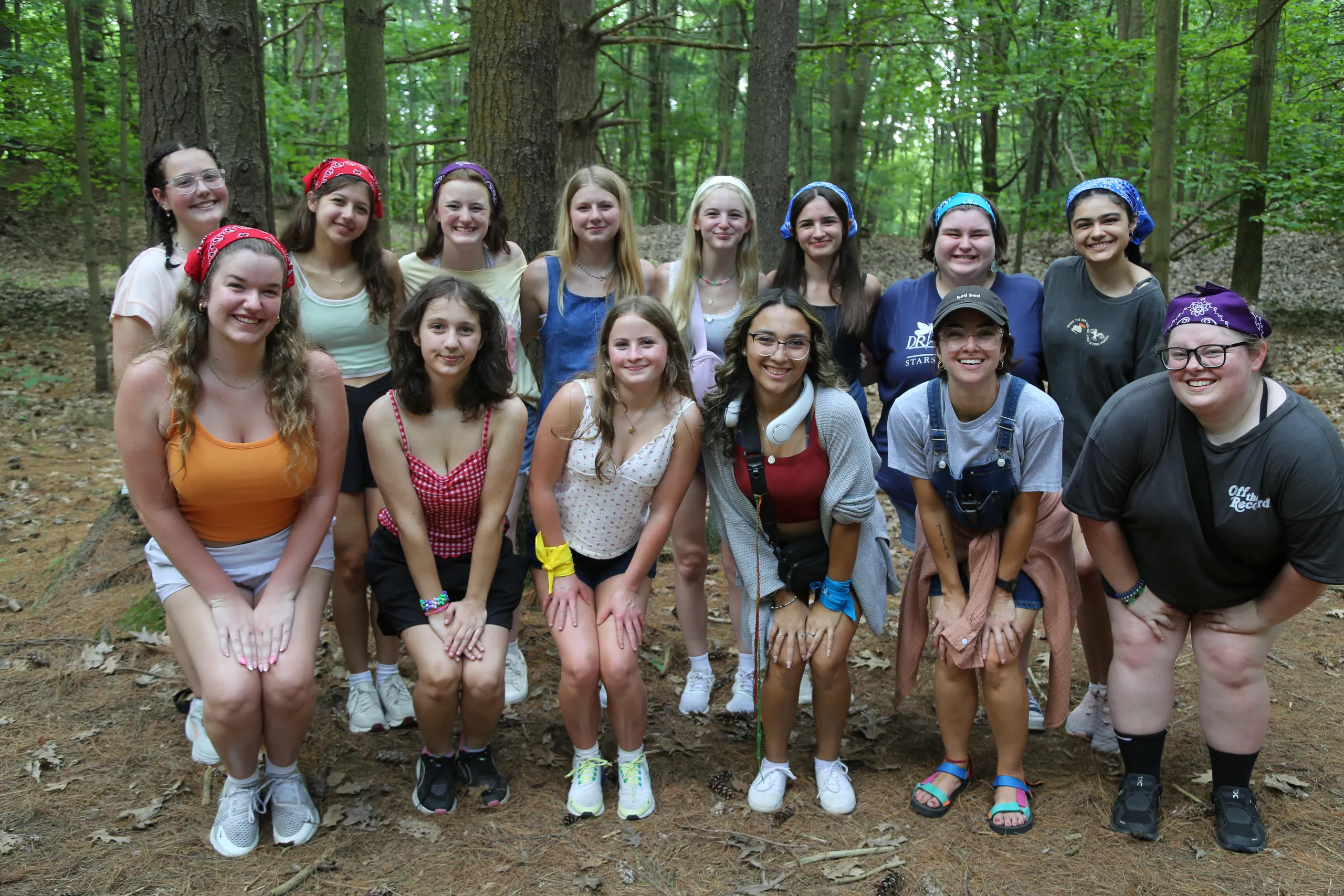 A group of campers smiling together on a forest trail