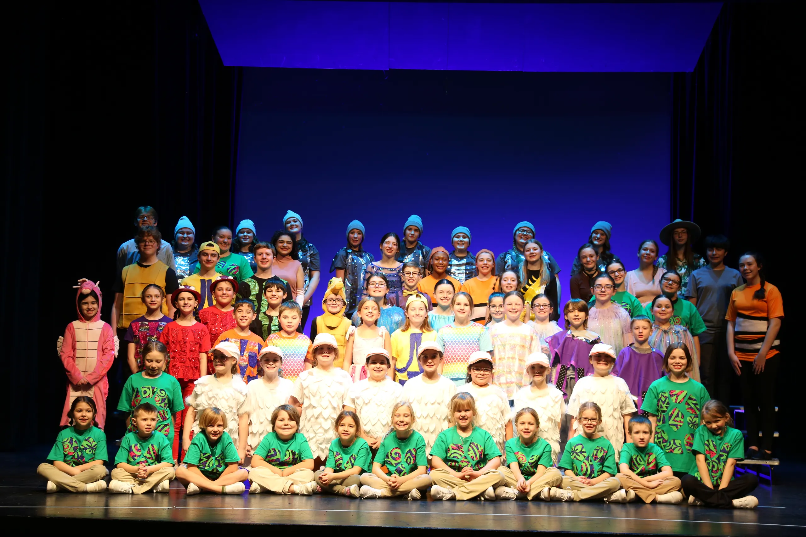 The full cast of Finding Nemo poses together on stage in colorful ocean-themed costumes